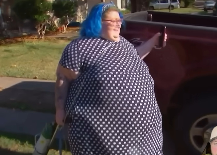 Dolly Martinez from My 600-Lb. Life smiling outside wearing a polka dot dress next to a red vehicle on a sunny day