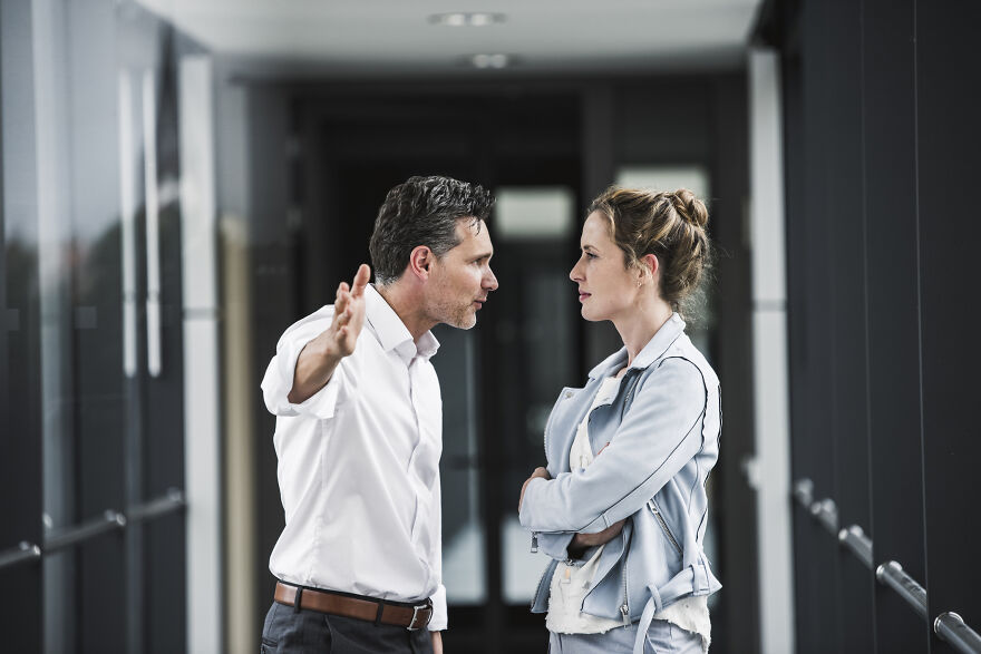 Man and woman having intense conversation in hallway representing outcast and thriving outside family narrative.