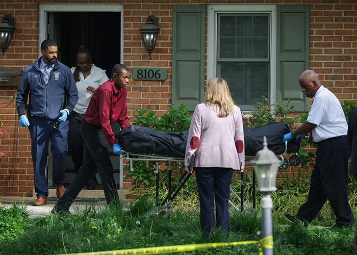 Forensic team removing a body on a stretcher outside a Virginia home in a case involving holes in her shirt.