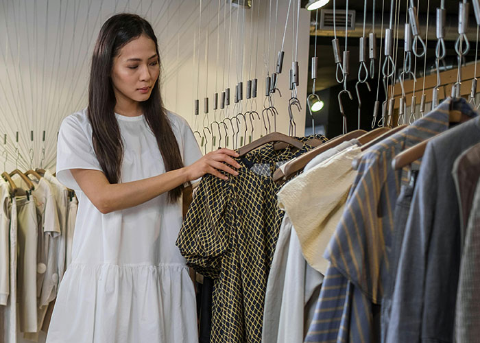 Woman examining clothes in a store, illustrating signs that indicate the economy is not doing well.