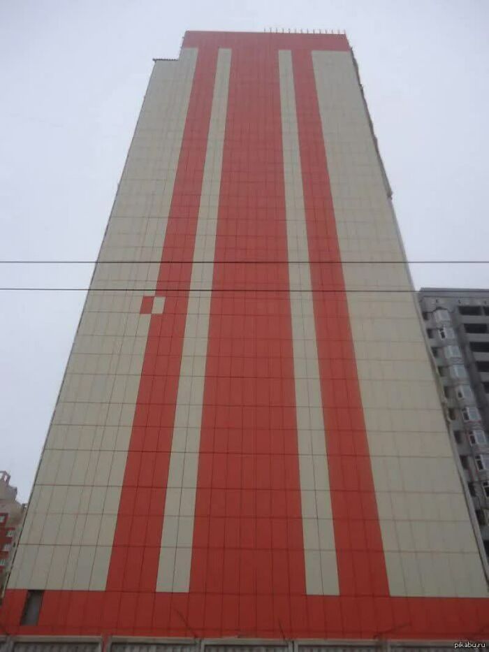 A tall, narrow building with white and orange vertical stripes, one tiny misplaced white square. A weird image.