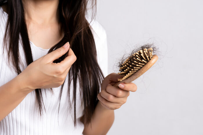 Woman seeing hair loss on a brush. A nasty and revolting thing often witnessed, potentially a medical concern.