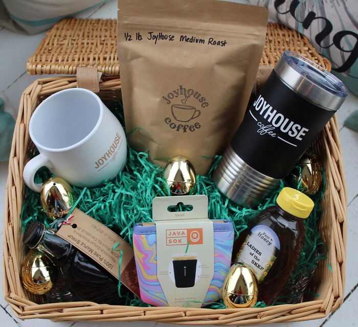 Easter basket ideas with coffee mugs, gourmet syrup, honey, and colorful toy stuffers in a woven basket.
