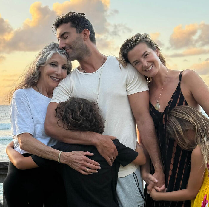 Family embracing on the beach at sunset with many reacting explosively to Blake Lively's lawsuit dismissal news