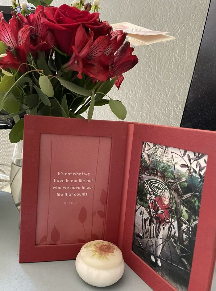Bouquet of red flowers next to a framed quote and photo, symbolizing touching stories about moms and family life.