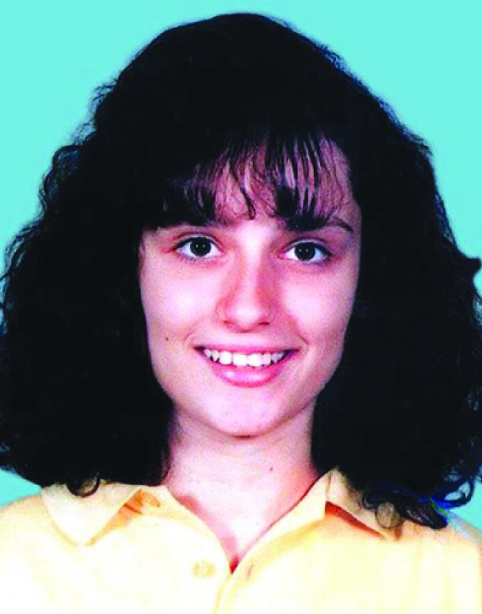 Young woman with curly hair smiling against a blue background, illustrating creepy and mysterious things that lose sleep over.