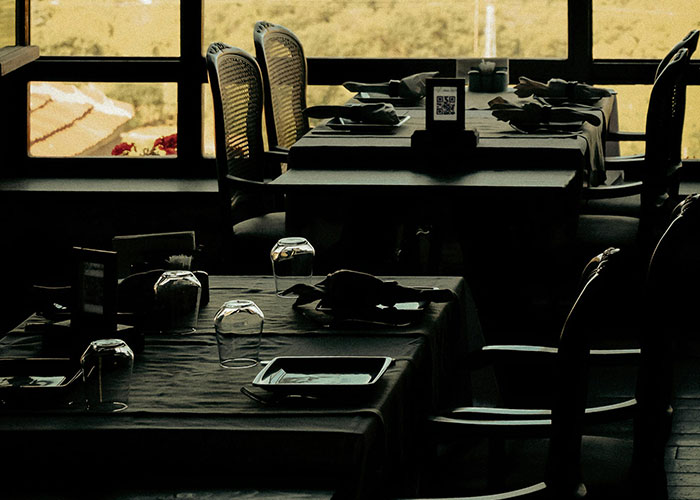 Empty restaurant tables with upside-down glasses, illustrating signs the economy is not doing well.