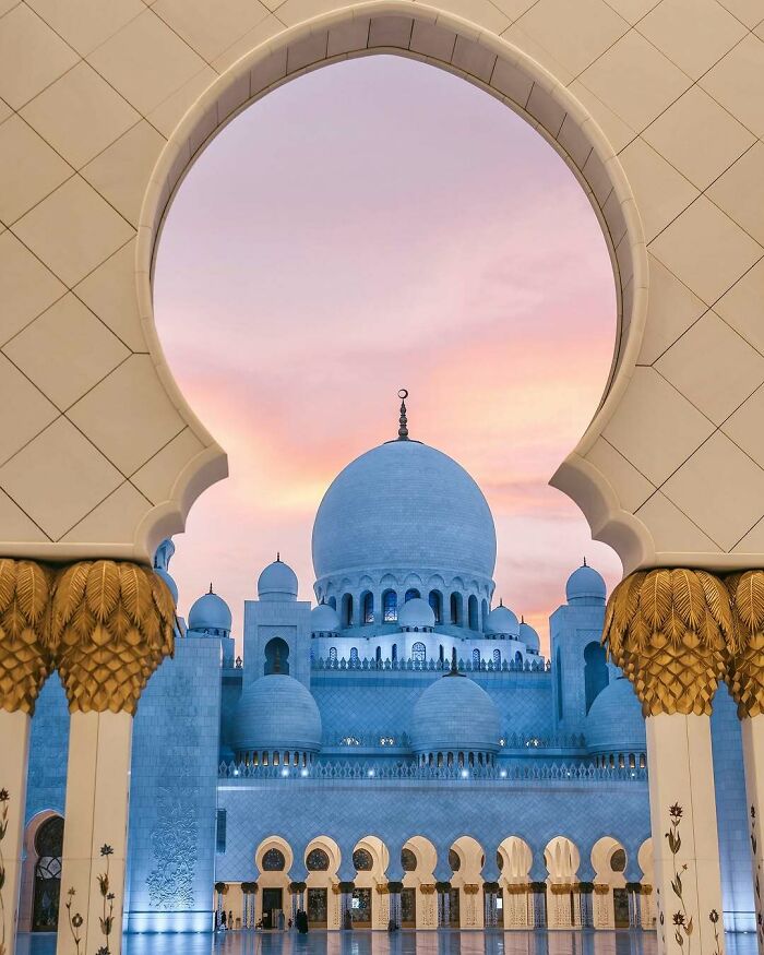 Sheikh Zayed Grand Mosque at dusk, framed by an arch, relevant to discussing countries with the worst work-life balance.
