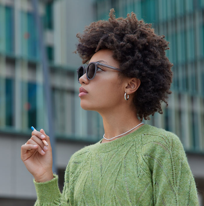 Woman with natural hair and sunglasses, holding a pencil. Highlighting favorite things about Black people.