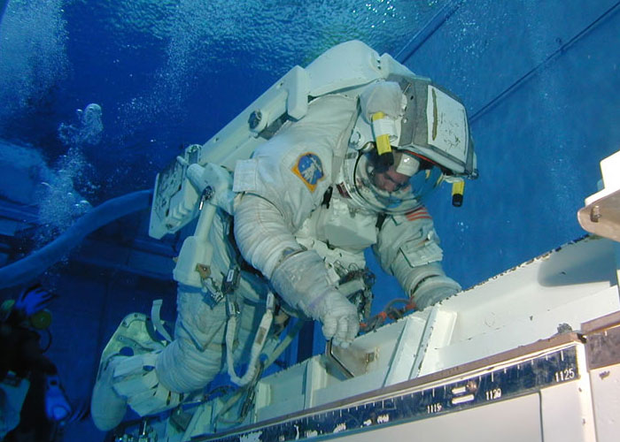 An astronaut in a spacesuit training underwater, simulating zero gravity. This exclusive access moment shows an astronaut couldn't believe their luck.