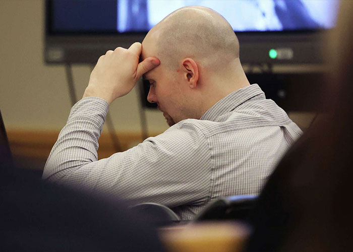 Bald man in a striped shirt, head in hand, appearing distressed. Likely related to the FedEx driver news.