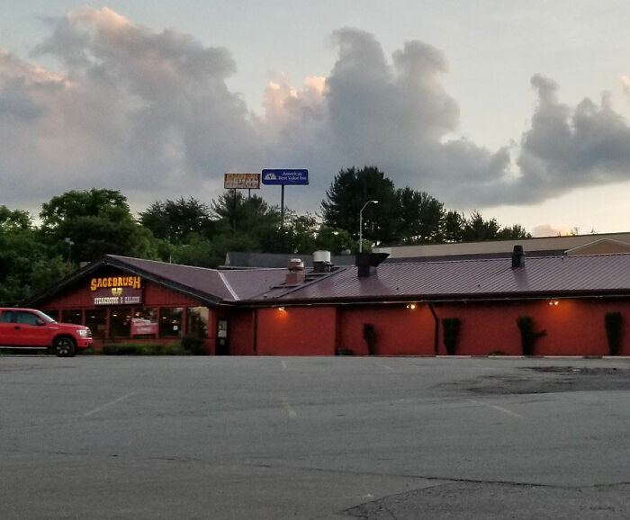 Parking lot and a red building under cloudy sky, evoking mysterious and creepy things that people lose sleep over.
