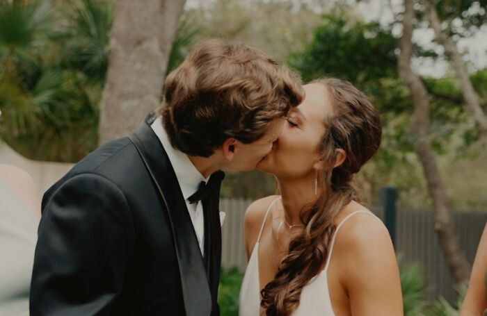 Couple dressed in wedding attire sharing a kiss outdoors, illustrating trashy tacky and distasteful wedding stories.