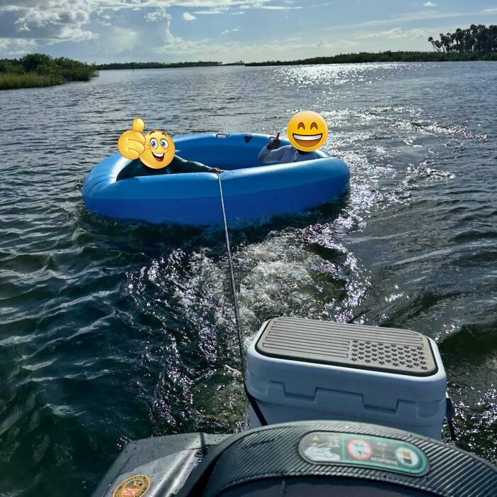 Two people with emoji faces in a blue inflatable being towed on water, capturing gut warning moments outdoors.
