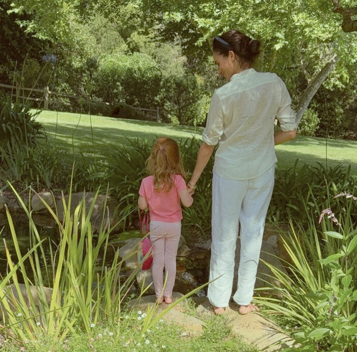 Meghan Markle with child in garden surrounded by greenery, highlighting Archie and Lilibet Easter clip backlash details.
