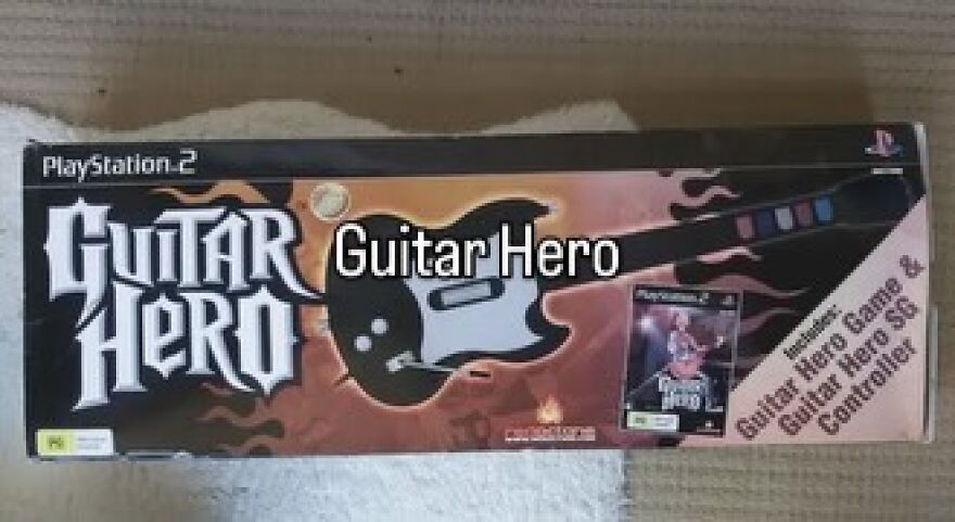 A Guitar Hero game box for PlayStation 2, featuring the game and a Guitar Hero SG Controller. Captures the vibe of growing up in the 2000s.