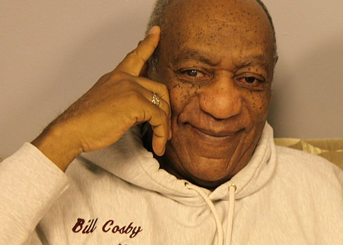 Bill Cosby wearing a white hoodie, smiling with a hand resting on his temple, highlighting beloved celebrities not nice in real life.