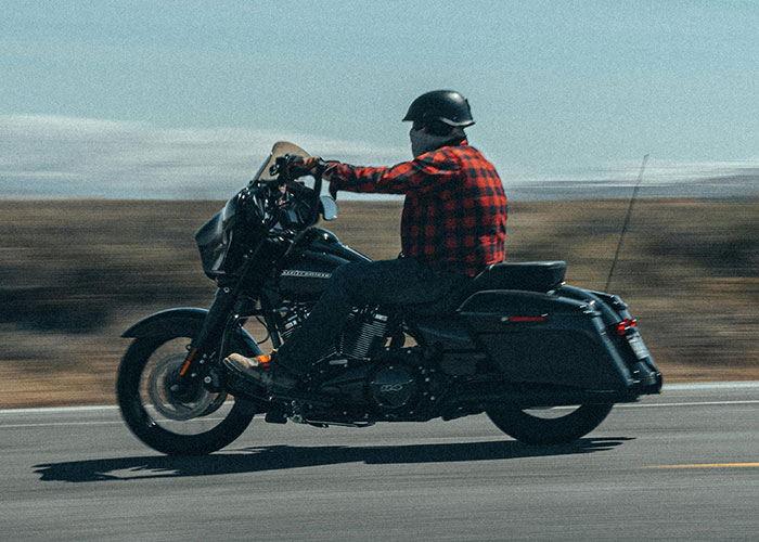 Motorcyclist wearing a helmet and red plaid jacket riding a motorcycle, illustrating dangers that seem less obvious.