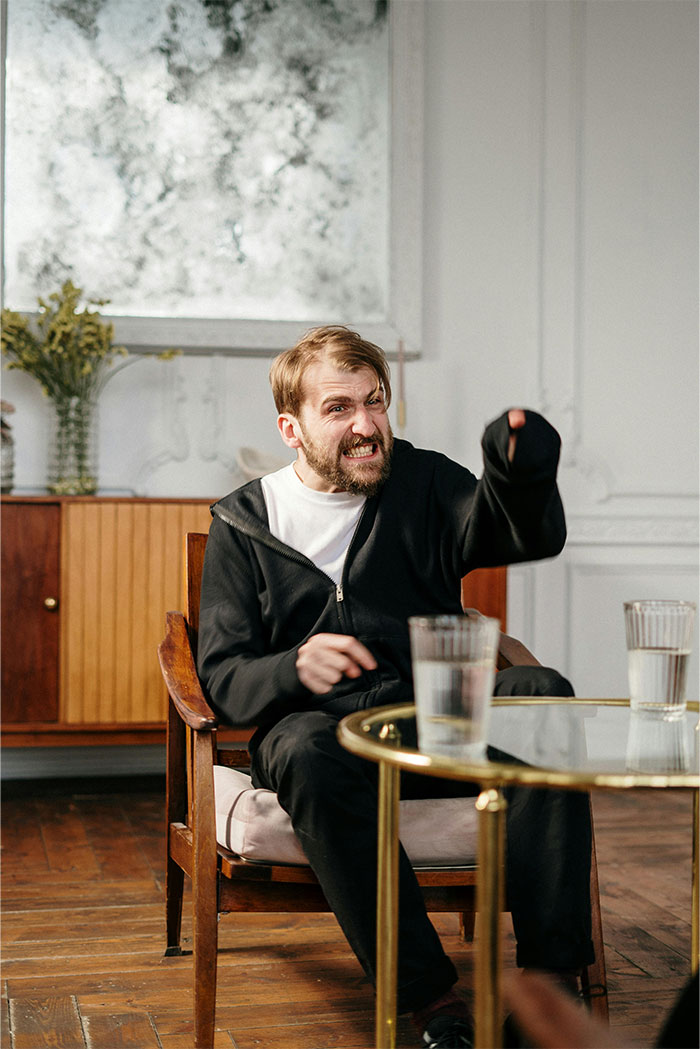 A man with a beard and intense expression, in a black hoodie, pointing angrily. This looks like a horrible first date.