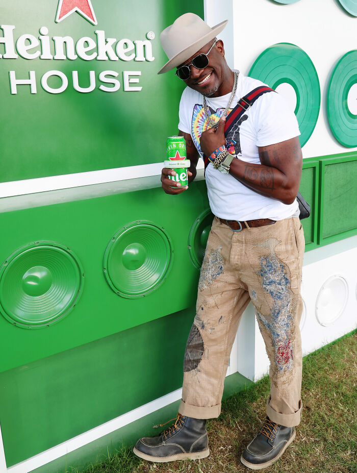 Man in a colorful outfit and hat posing with a drink at Coachella Weekend 2 showcasing fashion fails and absurd looks.