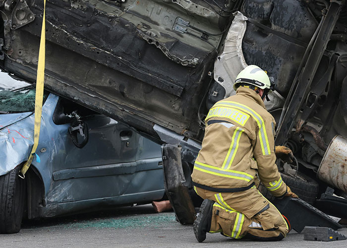 Firefighter inspecting overturned vehicles at accident scene, illustrating random signs showing economy is struggling.