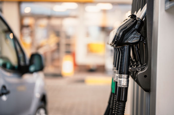 Fuel pump nozzles at a gas station, with a blurred car in the background. Related to revenge against toxic bosses.