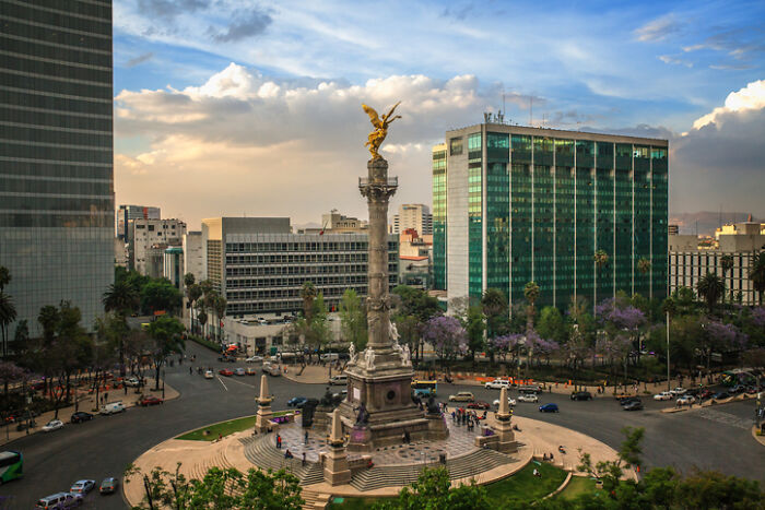 Aerial view of Mexico City's Angel of Independence roundabout with traffic and modern buildings. Focus on Work-Life Balance.