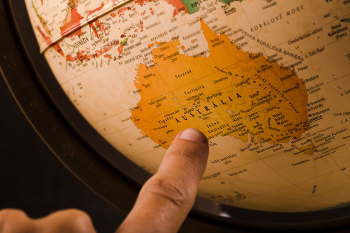 A person's finger points at Australia on an antique globe, representing moments when someone realized how dumb someone they're dating was.