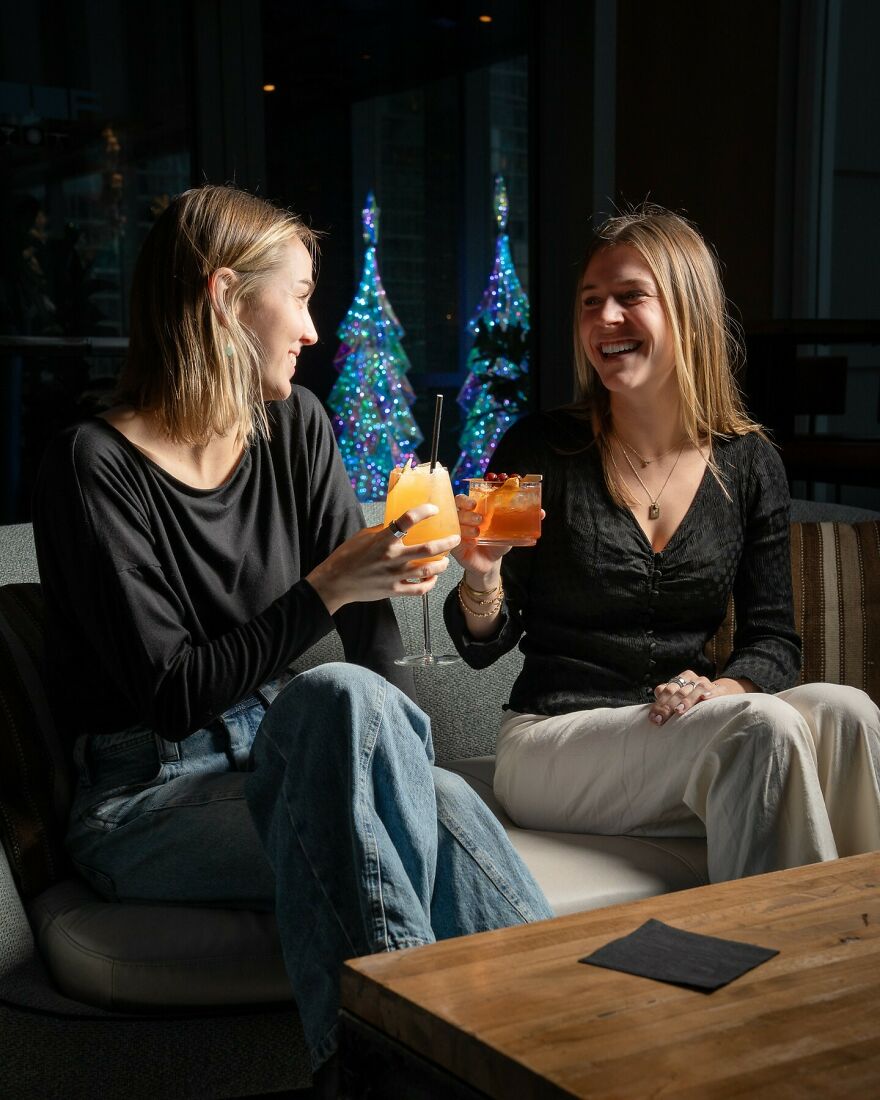 Two happy women toasting drinks, celebrating financial independence after escaping financial a***e in marriage.