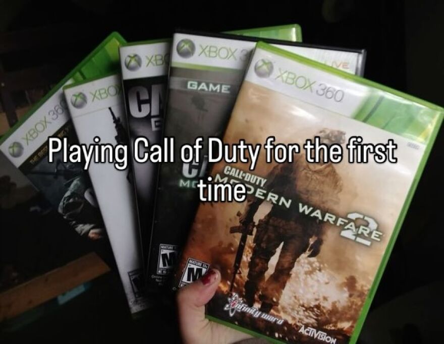 A hand holds a Call of Duty Modern Warfare 2 game for Xbox 360, surrounded by other Xbox games, capturing the vibe of growing up in the 2000s.