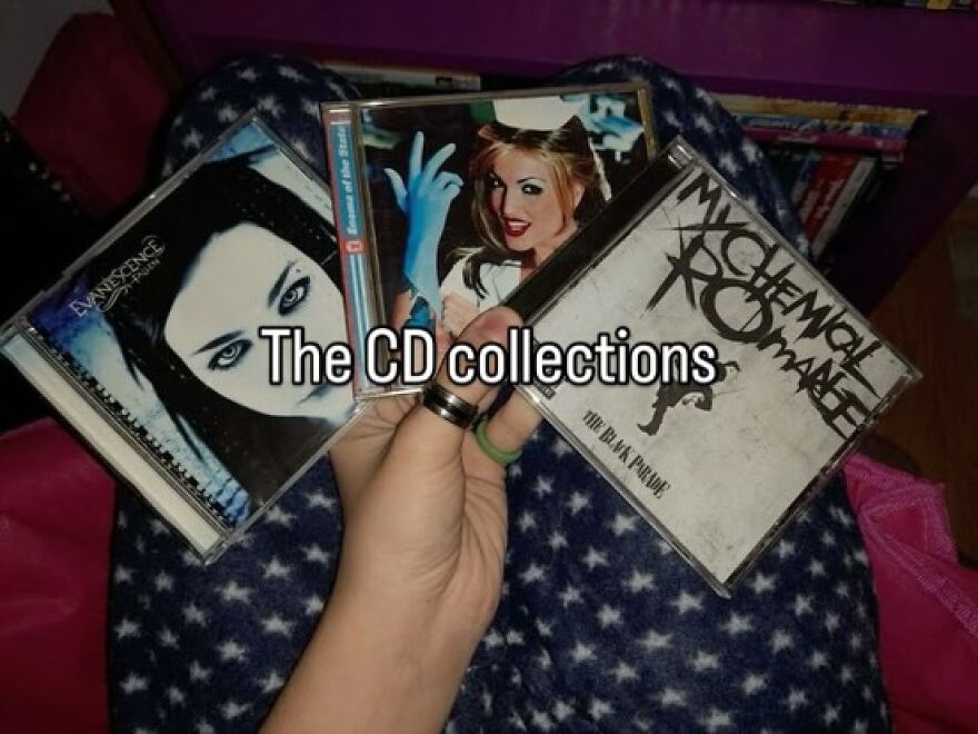 A hand holds three nostalgic CD covers including Evanescence and My Chemical Romance, capturing the vibe of growing up in the 2000s.