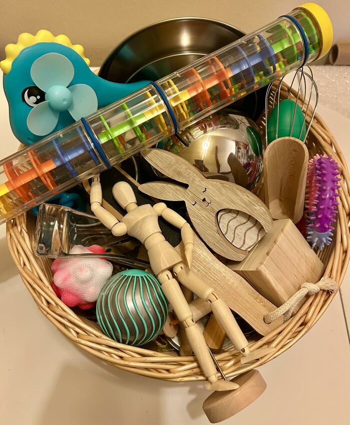 Easter basket ideas by age showing toy stuffers including wooden bunny, sensory toys, and colorful balls in wicker basket.