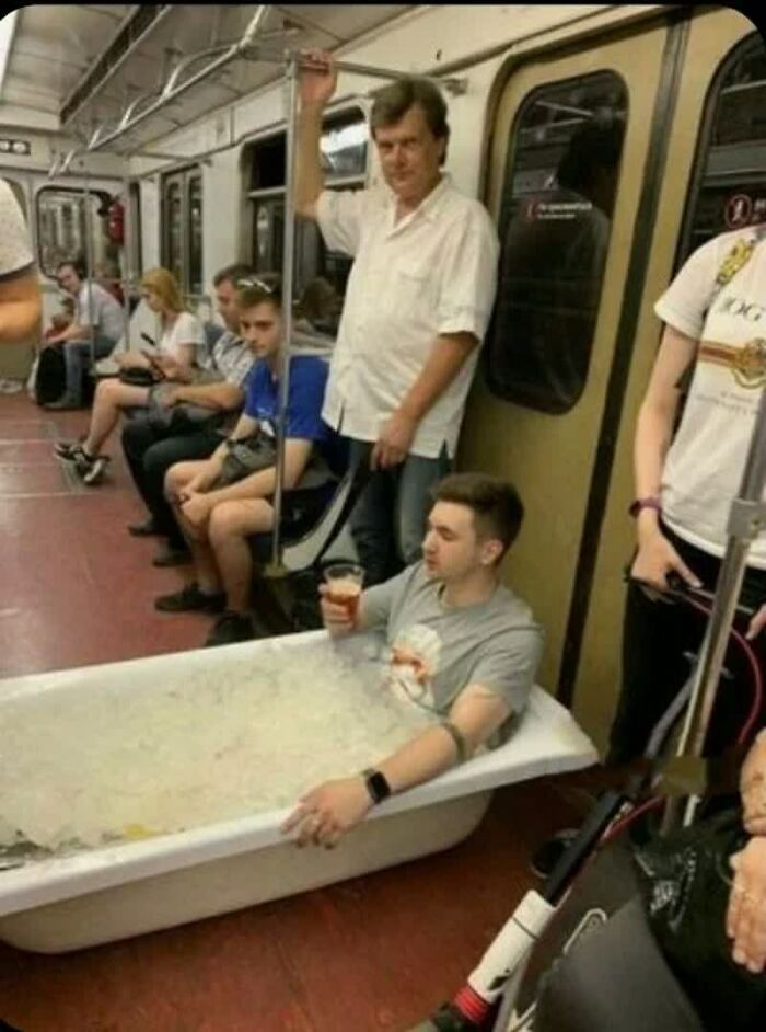 A man in a bathtub full of ice on a subway, holding a drink. This is one of many weird images.