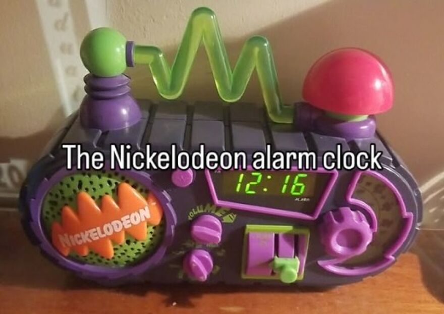 A colorful Nickelodeon alarm clock from the 2000s, featuring a green digital display and unique purple and orange details.