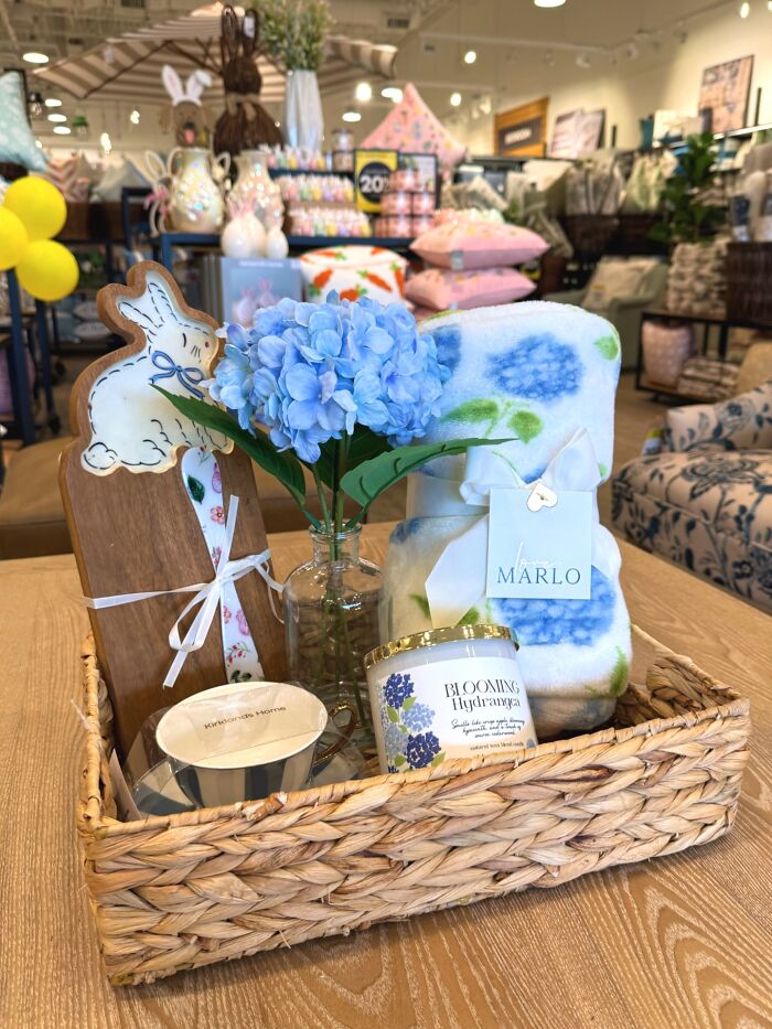 Woven Easter basket with hydrangea flower, decorative candle, cozy blanket, and bunny-shaped wooden board.