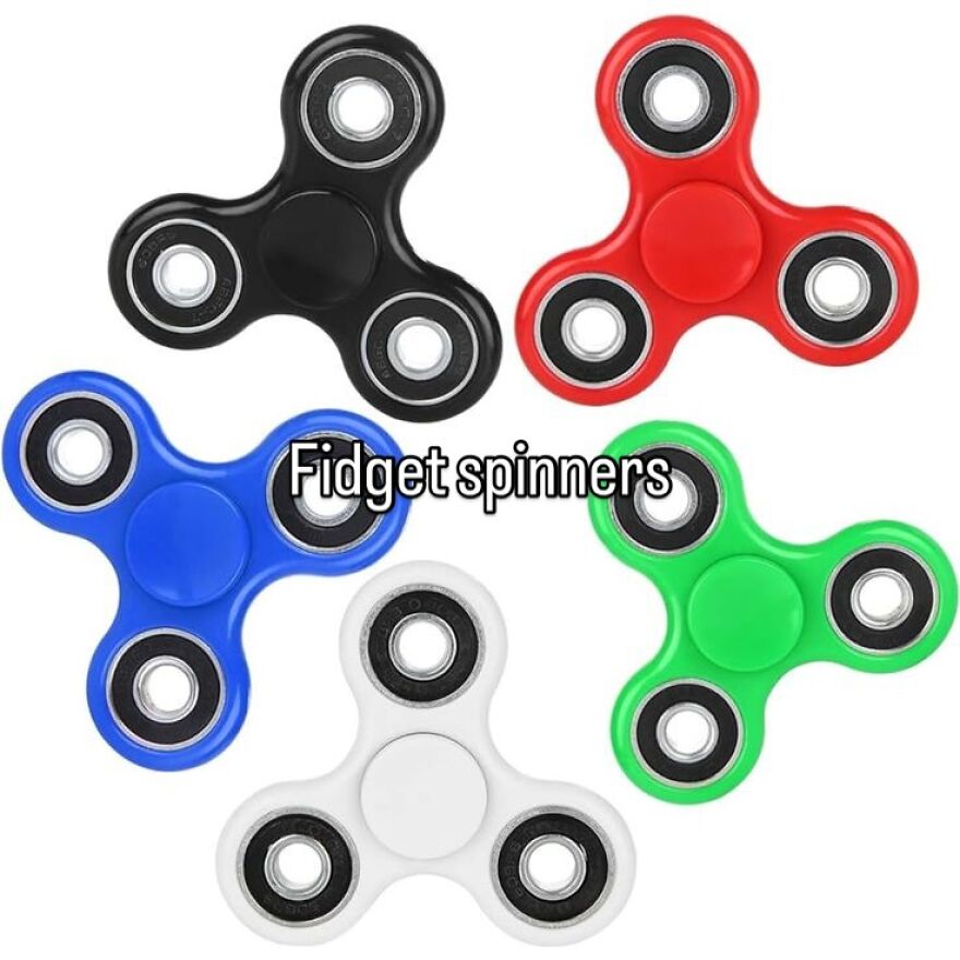 Five colorful fidget spinners: black, red, blue, green, and white. Captures the vibe of growing up in the 2000s.
