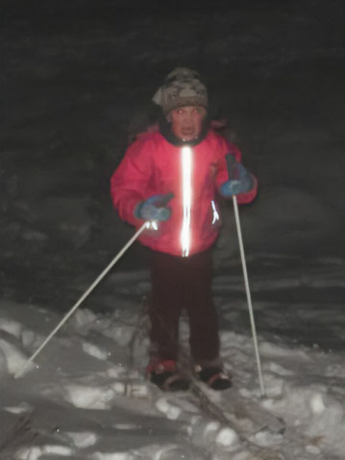 Child struggling to ski in the snow at night, a funny and chaotic childhood photo moment captured outdoors.
