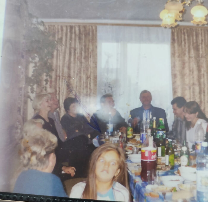 Chaotic childhood photo of a family gathering with kids making funny faces around a crowded dining table.