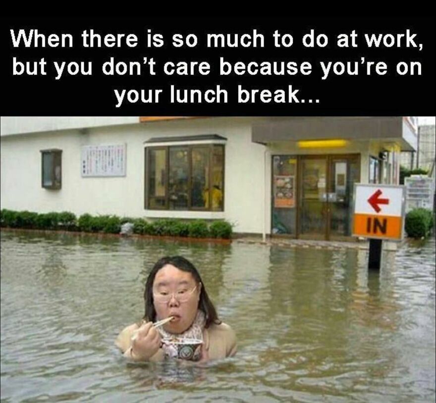 Person eating lunch calmly while standing in floodwater outside a workplace, illustrating work memes about job frustrations.