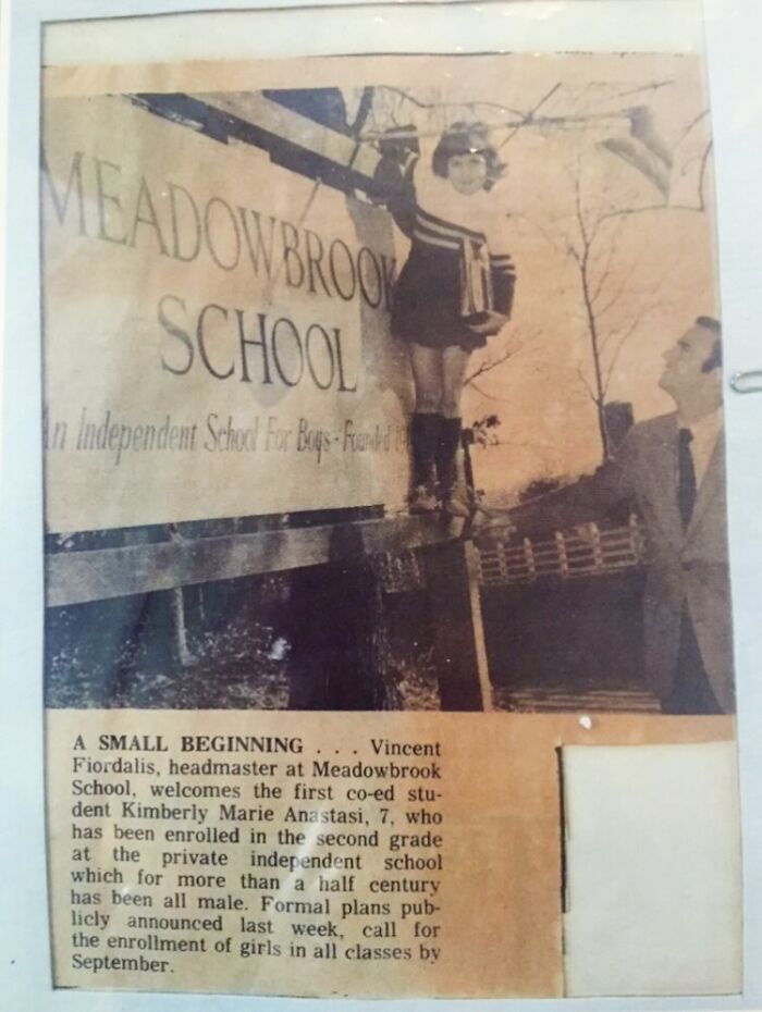 Vintage photo of a young girl with a man by a school sign, sharing amazing and interesting stories about their moms.