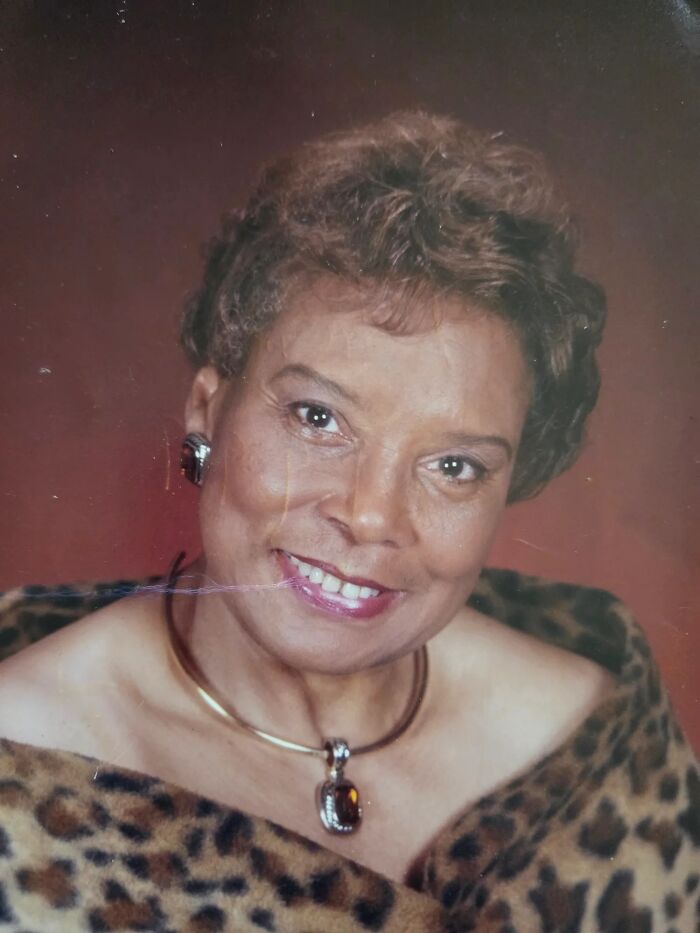 Portrait of a smiling woman wearing a leopard print shawl and jewelry, representing amazing and interesting stories about moms.
