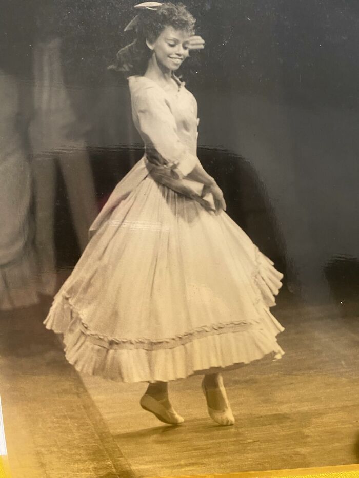 Young woman in vintage dress dancing on stage, capturing a timeless moment in stories about moms.