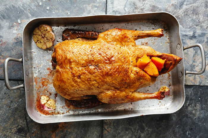 Golden roasted duck with squash and garlic in a pan. Medical workers witness nasty and revolting things, unlike this.