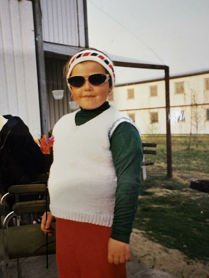 Child wearing vintage clothes and sunglasses, posing outdoors in a funny and chaotic childhood photo moment.