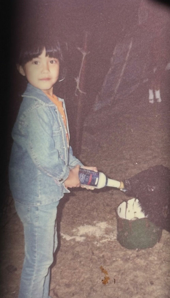 Child in denim jacket holding a bottle near a mannequin head in a funny and chaotic childhood photo.