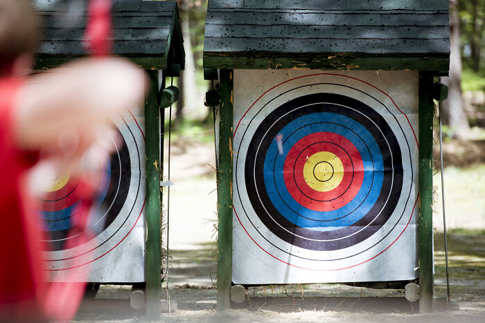 Child aiming at archery targets outdoors, illustrating kids' lack of survival instincts and childhood mistakes.