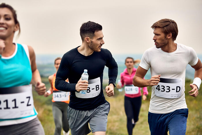 Outdoor race, several runners, with two men in the foreground exchanging tense glances, evoking friendship betrayals.
