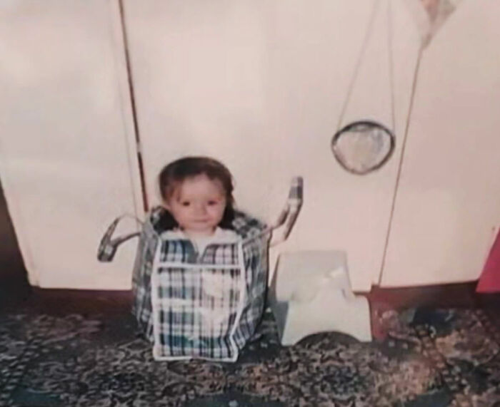Toddler stuck inside a laundry basket in a funny and chaotic childhood photo at home.