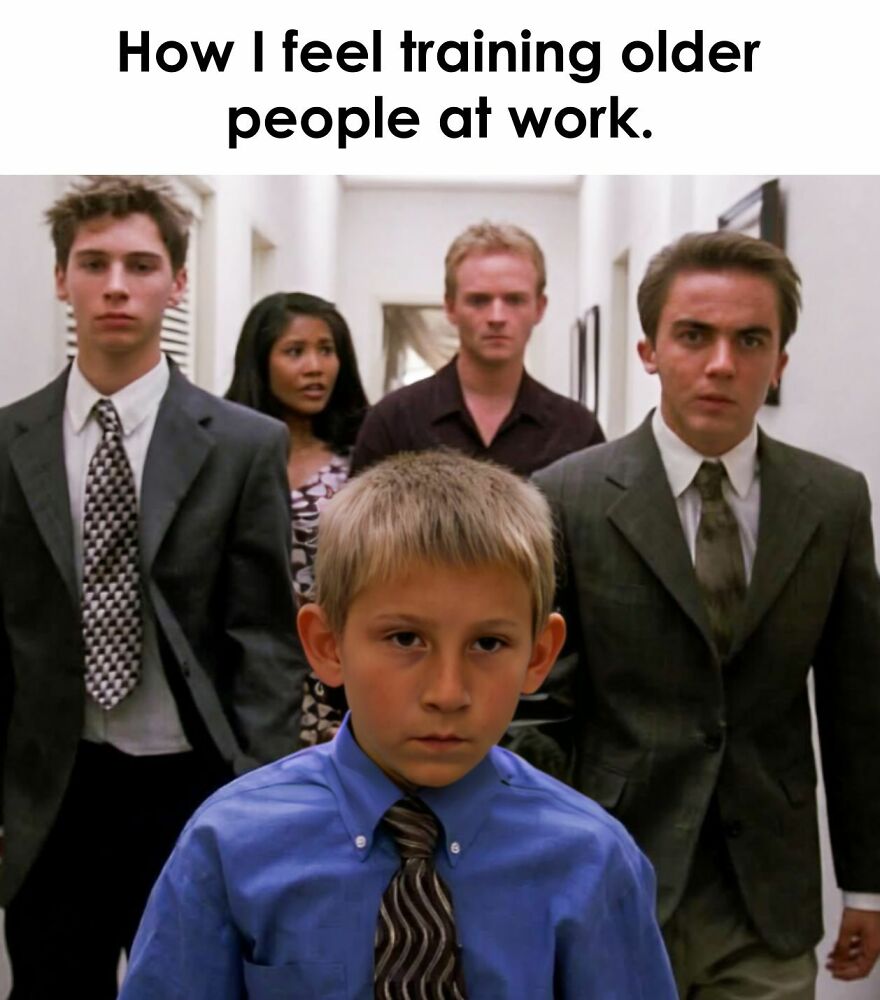Young boy in a blue shirt and tie leading adults in suits, expressing a work meme about training older people at work.