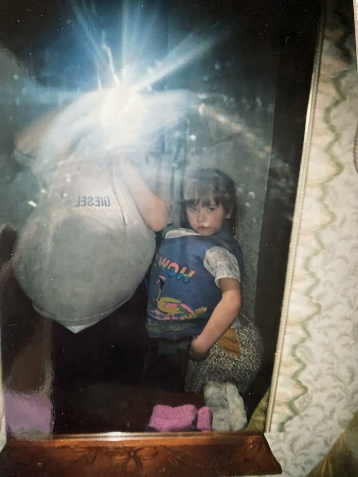 Funny and chaotic childhood photo of kids posing in front of a mirror with playful and quirky expressions inside a home.